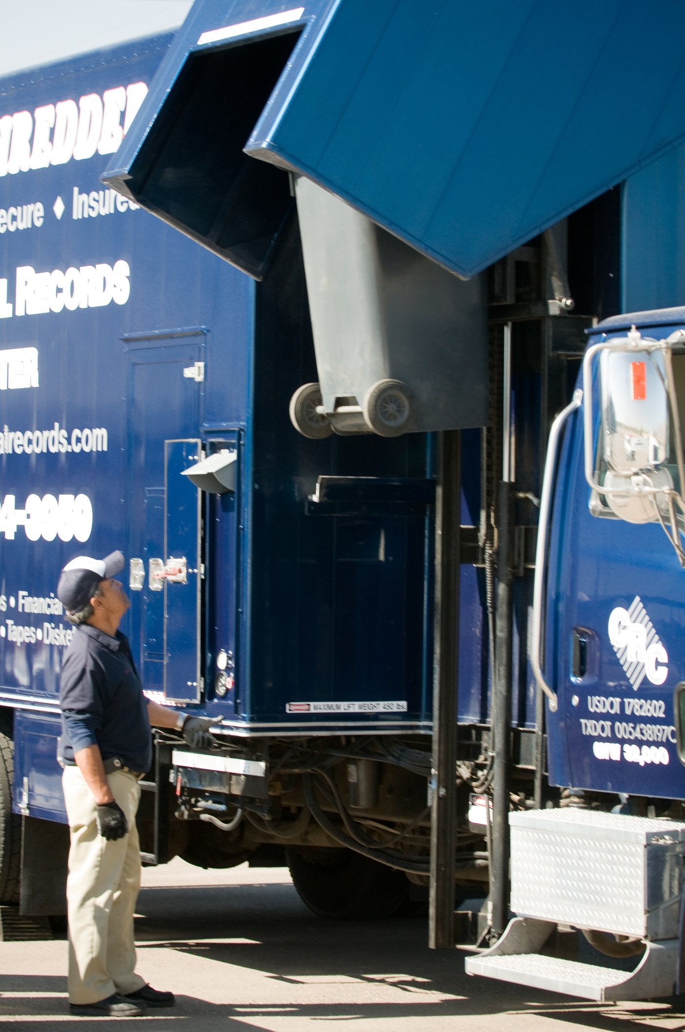 A worker watching a bin of documents being lifted into a mobile shredding truck