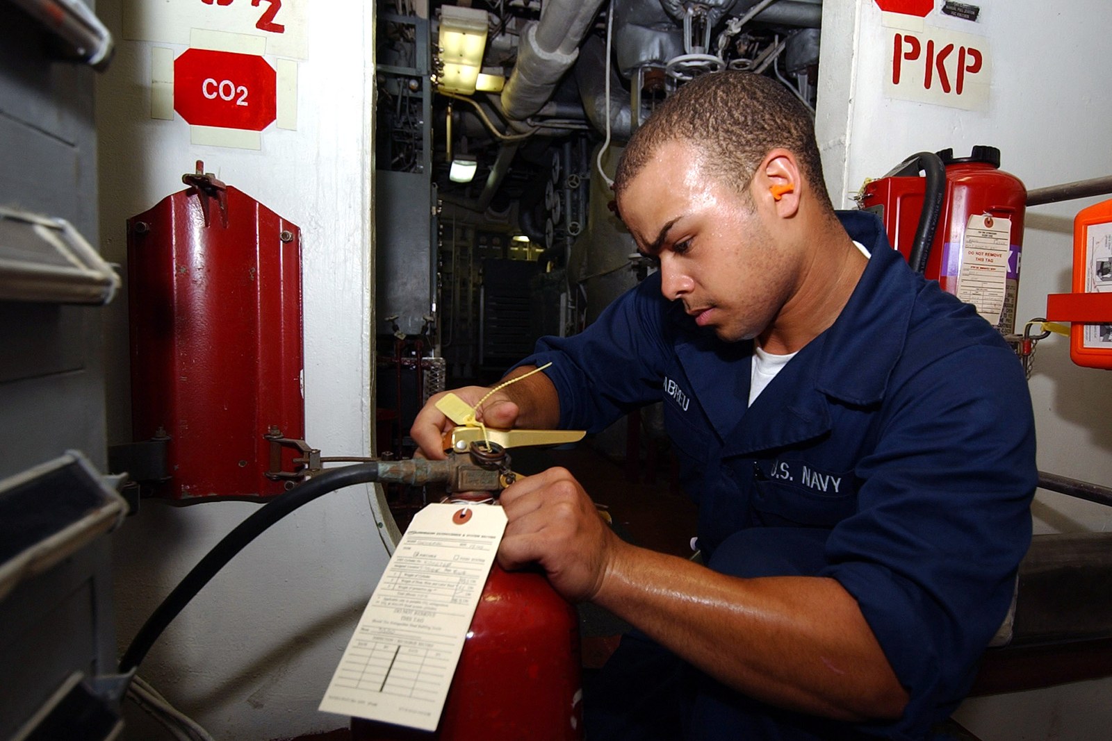 A technician checking a fire extinguisher during a maintenance inspection