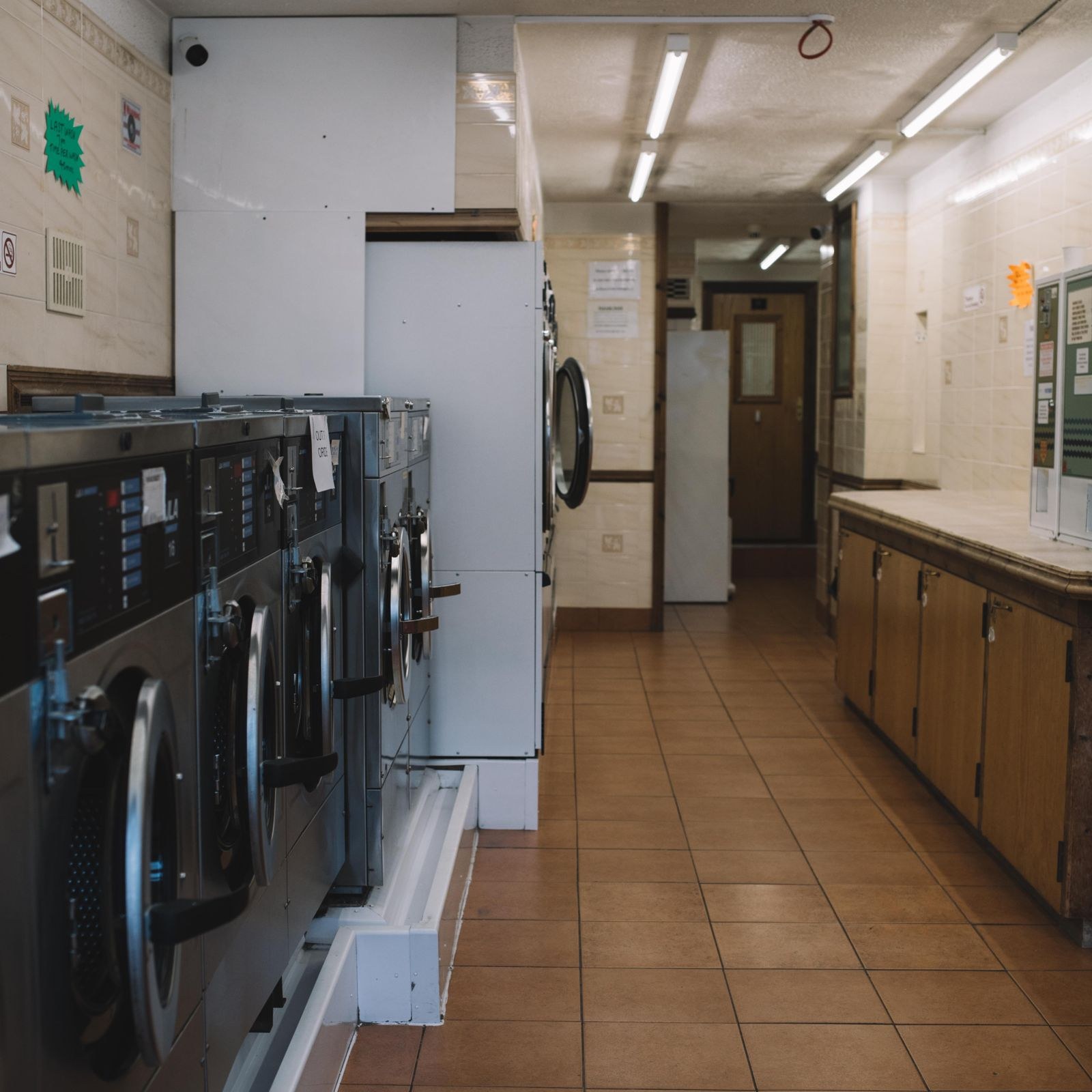 Interior of a laundromat with a row of washing machines and a folding counter