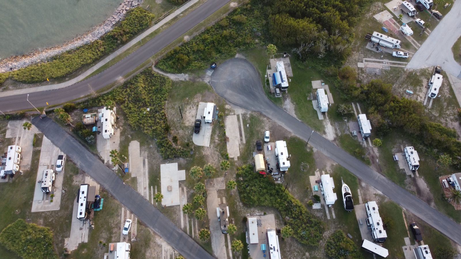Aerial view of an RV park with rigs on concrete pads near the shore
